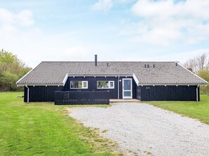 A single-story building with a tiled roof, a front door, and a gravel driveway leading to a wooden fence. - 4 Star Holiday Home in Hjorring (Hjørring)