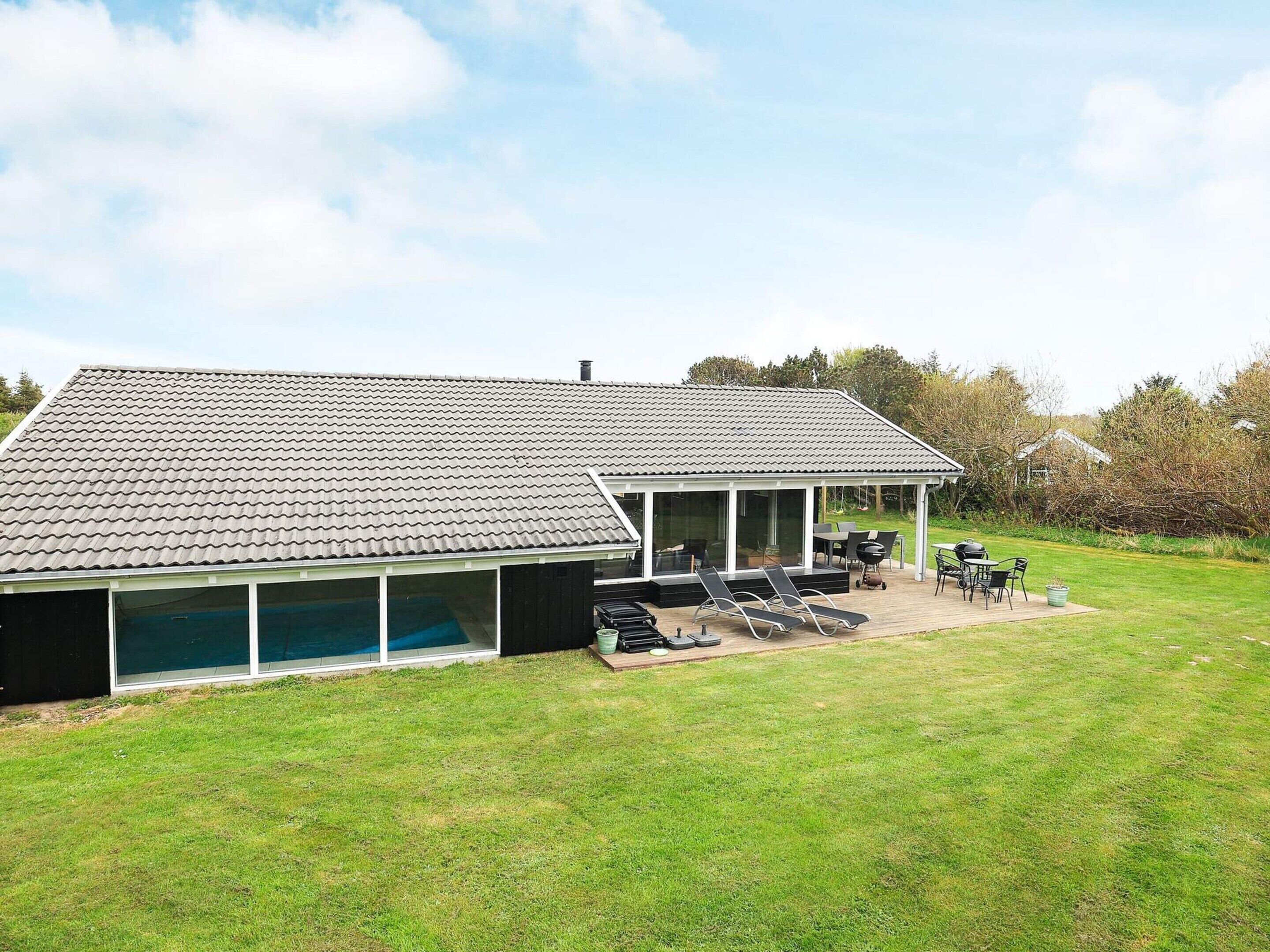 A house with a covered patio area, a swimming pool, and a grassy backyard.