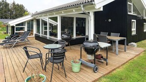 A covered outdoor deck with lounge chairs, a table, and a grill. - 4 Star Holiday Home in Hjorring (Hjørring)