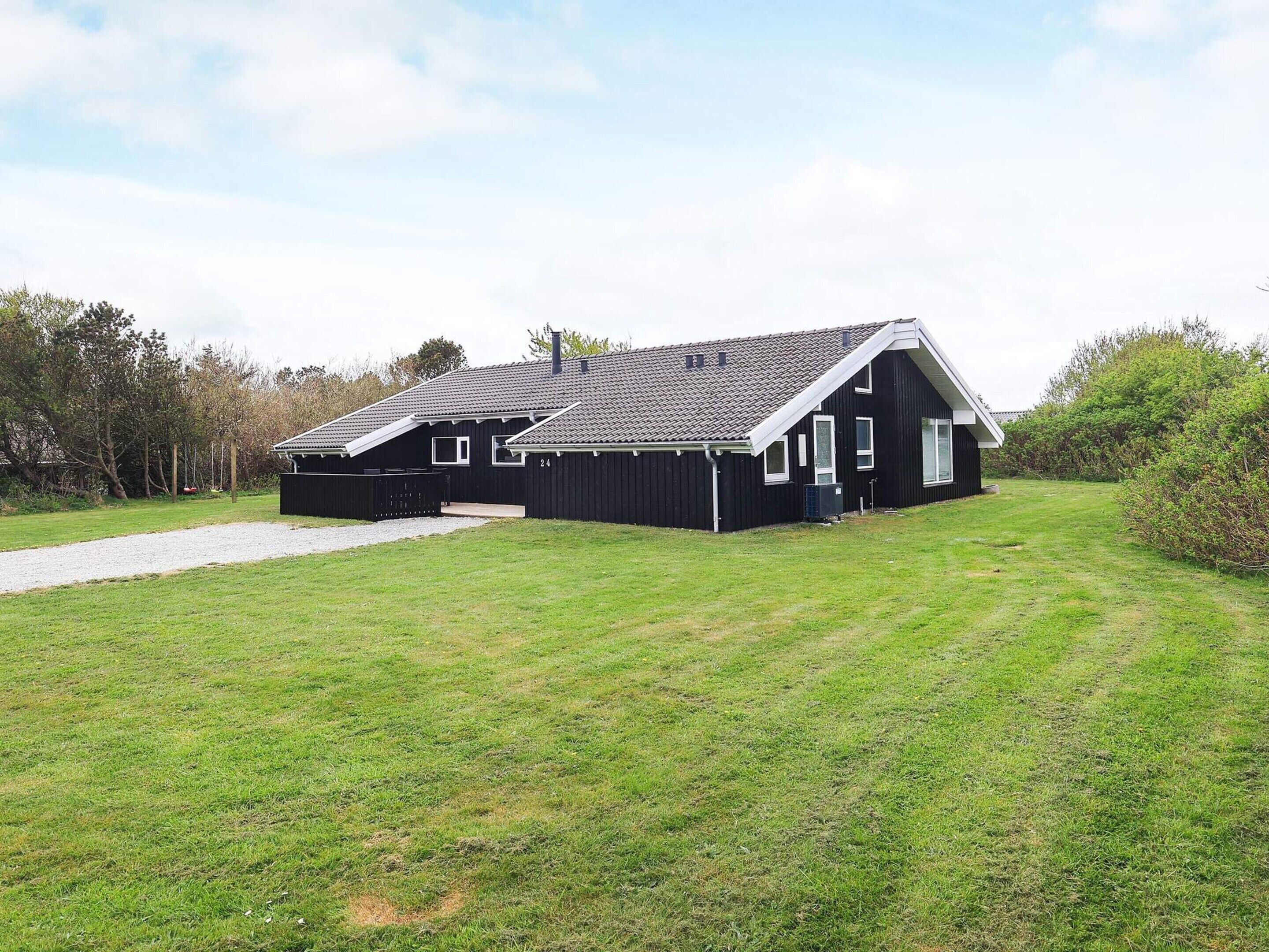 A black building with a sloped roof and a paved driveway.