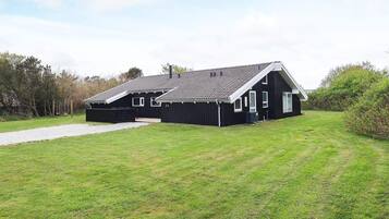 A black building with a sloped roof and a paved driveway.
