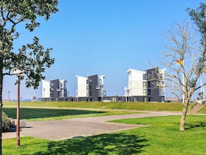 A modern residential building complex with multiple apartment buildings, a well-maintained lawn, and a clear sky. - Holiday Home in Wendtorf (Schönberg)