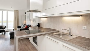 Eine moderne Küche mit weißen Schränken, einer Edelstahlspüle und einem eingebauten Backofen.