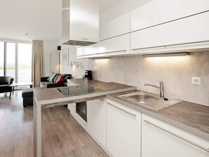 A modern kitchen with white cabinetry, a stainless steel sink, and a built-in oven. - Holiday Home in Wendtorf (Schönberg)
