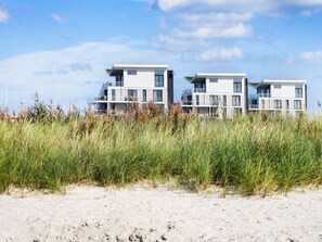 A modern beachfront property with multiple levels, large windows, and a flat roof design.