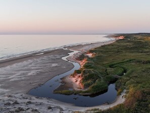 A coastal landscape with a beach, a small water body, and grassy terrain. - 4 Star Holiday Home in Bindslev (Bindslev)