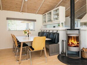 A cozy room with a dining table, chairs, a bench, a fireplace, and built-in cabinets. - 4 Star Holiday Home in Bindslev (Bindslev)