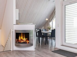 A modern interior with a fireplace, dining area, and large windows. - Holiday Home in Wendtorf (Wendtorf)