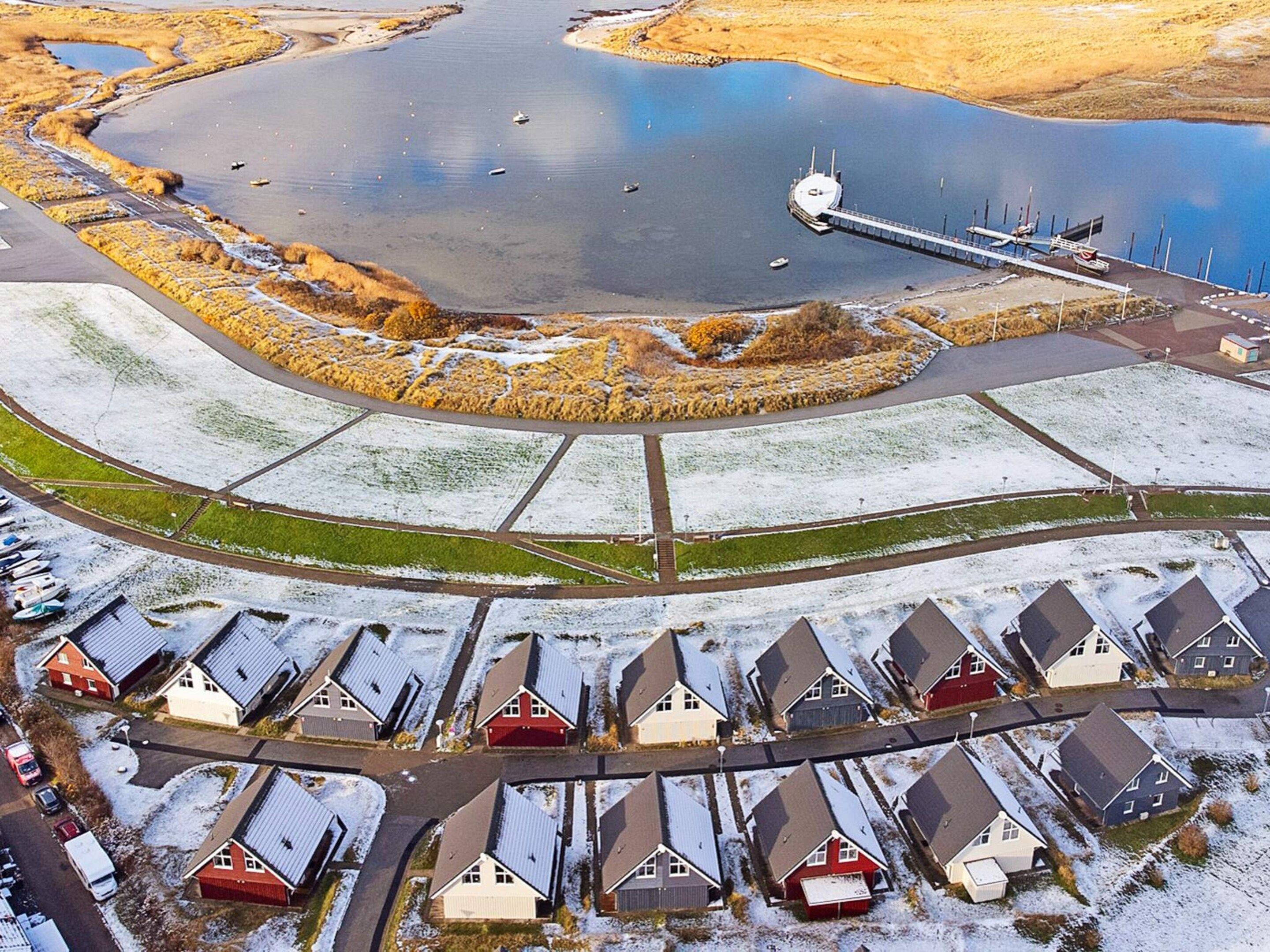 An aerial view of a residential area with houses, a dock, and a body of water.