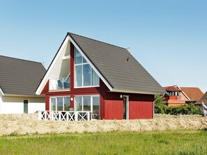 Una casa roja de dos pisos con un balcón blanco y una valla blanca.