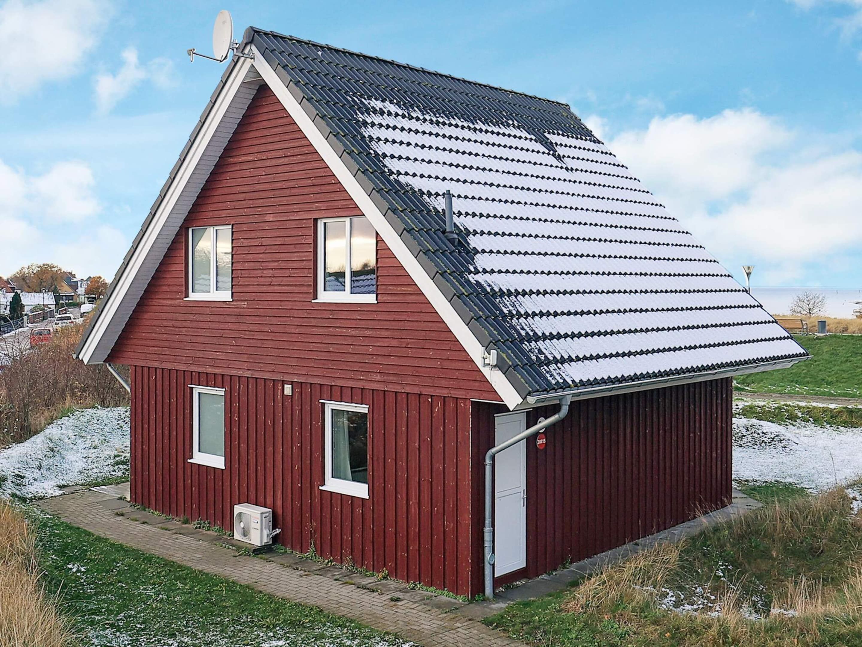 A red wooden house with a sloped roof, a garage, and a satellite dish.