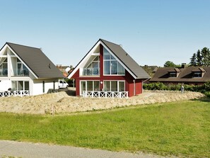 A residential area with two houses, one with a red exterior and the other white, both featuring pitched roofs and large windows.