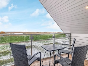 An outdoor patio with a table and chairs, a view of a field, and a building in the background. - Holiday Home in Wendtorf (Wendtorf)