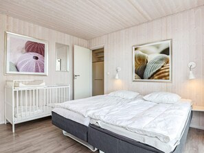 A bedroom with a bed, a white dresser, a mirror, and two wall-mounted lights.