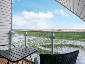 Ein Balkon mit Blick auf eine Wiese und eine entfernte Küste.