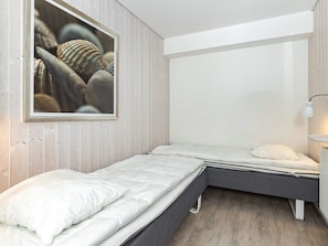 Un dormitorio con dos camas individuales, una mesita de noche con lámpara y un cuadro enmarcado en la pared.