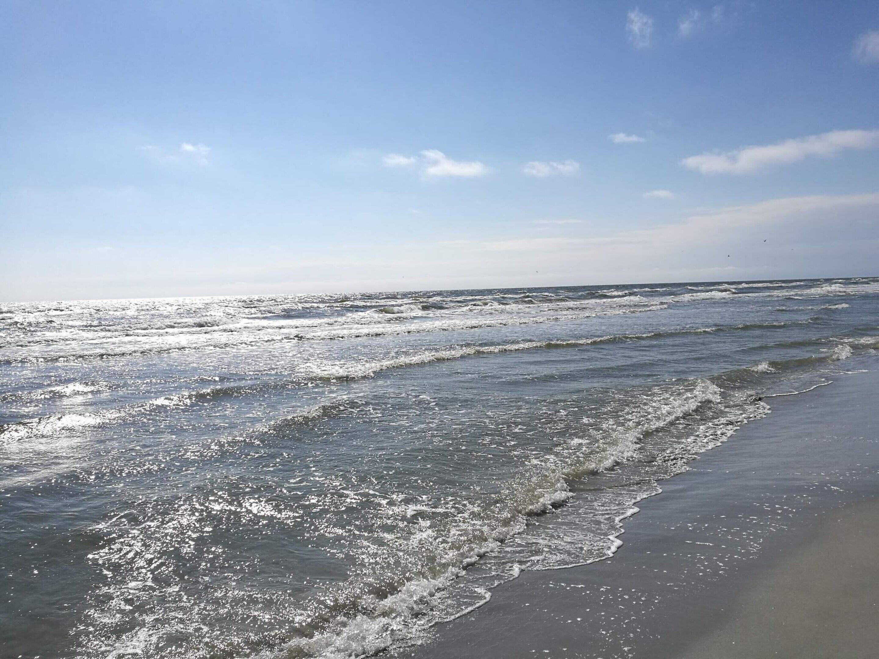 A beach with waves and a clear sky.