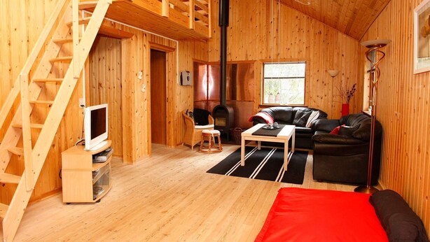 A wooden interior with a staircase, a fireplace, a sofa, and a television. - 4 Star Holiday Home in Hals (Hals)