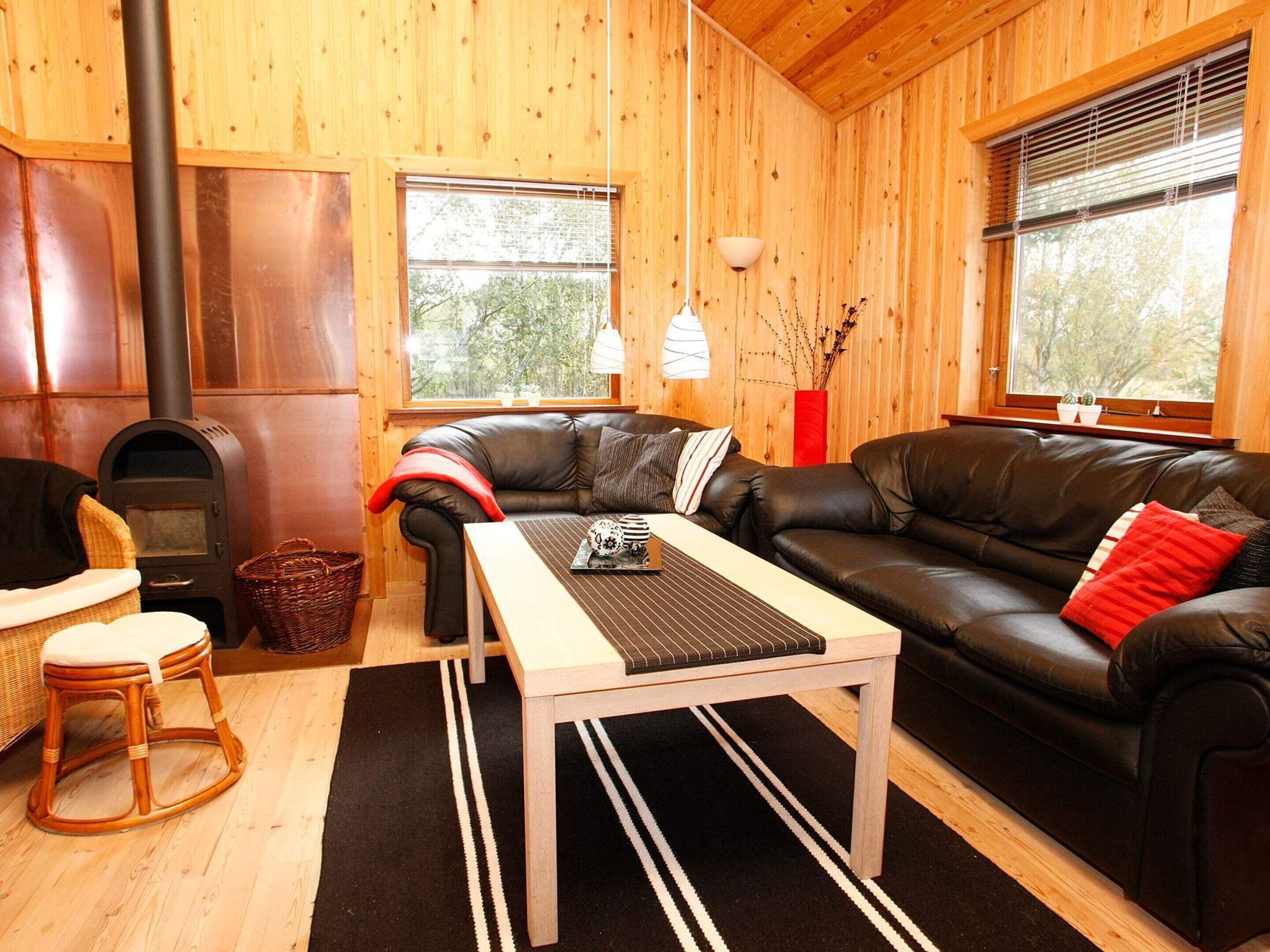 A cozy living room with a fireplace, leather sofa, and a dining table.