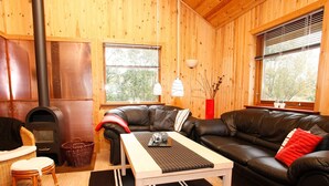 A cozy living room with a fireplace, leather sofa, and a dining table. - 4 Star Holiday Home in Hals (Hals)