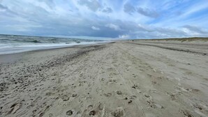 A beach with footprints leading to the water, a wide sandy path, and dunes in the background. - 6 Person Holiday Home in Henne (Henne)