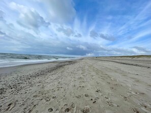 A beach with footprints leading to the water, a wide sandy path, and dunes in the background. - 6 Person Holiday Home in Henne (Henne)