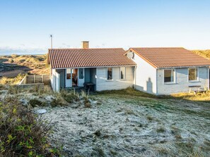 A two-story house with a metal roof, a satellite dish, and a small porch. - 6 Person Holiday Home in Henne (Henne)