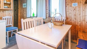 A wooden interior with a white table, two chairs, a red pendant light, and a window with curtains. - 6 Person Holiday Home in Henne (Henne)