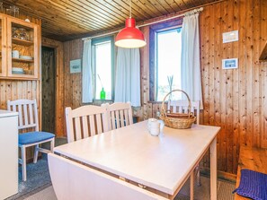 A wooden interior with a white table, two chairs, a red pendant light, and a window with curtains. - 6 Person Holiday Home in Henne (Henne)