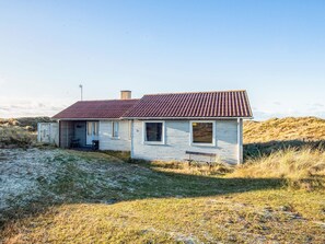 Ein einstöckiges Haus mit rotem Dach, einer Veranda und einem kleinen Vorgarten.