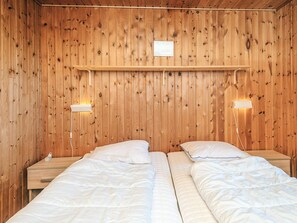 A room with wooden walls, two beds with white bedding, bedside tables, and wall-mounted lamps. - 6 Person Holiday Home in Henne (Henne)