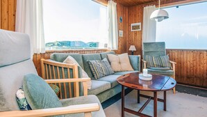 A cozy cabin interior with a wooden ceiling, a sofa, two armchairs, a small table, and a view of the outdoors. - 6 Person Holiday Home in Henne (Henne)