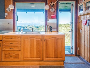 A kitchen with wooden cabinets, a sink, and a view of a mountainous landscape. - 6 Person Holiday Home in Henne (Henne)