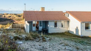 A single-story house with a sloped roof, a visible chimney, and a small porch area. - 6 Person Holiday Home in Henne (Henne)