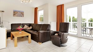 A modern living room with a sofa, a recliner, a coffee table, and a painting on the wall. - Holiday Home in Grossenbrode (Grossenbrode)