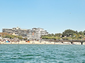 A coastal hotel with multiple floors, a beach in the foreground, and a bridge connecting to the mainland. - Holiday Home in Grossenbrode (Grossenbrode)