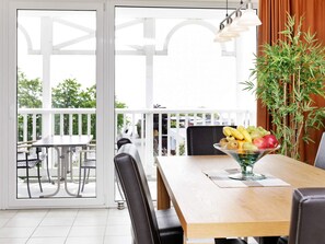 A dining area with a wooden table, chairs, and a fruit bowl. - Holiday Home in Grossenbrode (Grossenbrode)