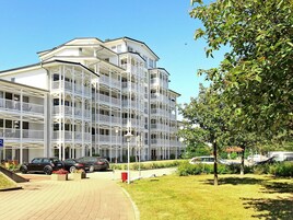 A multi-story hotel with balconies, a parking area, and a well-maintained lawn.