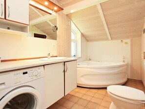 A compact bathroom with a washing machine, a sink, a bathtub, and a toilet. - Holiday Home in Otterndorf (Otterndorf)
