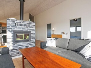 A modern living room with a fireplace, a sofa, and a wooden table. - 12 Person Holiday Home in Lokken-by Traum (Lokken)