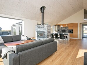 A modern living room with a fireplace, a dining area, and a kitchen.