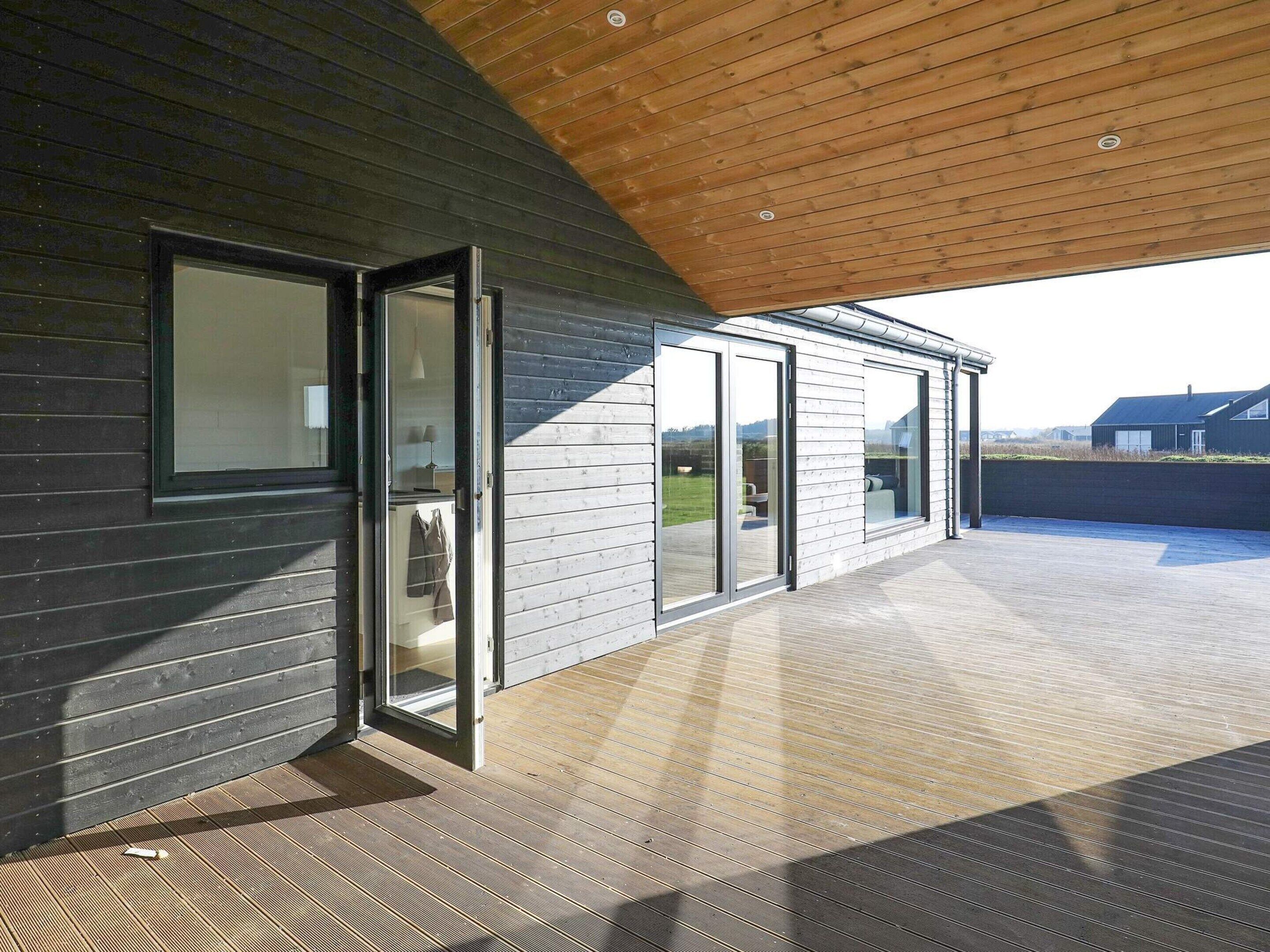 A modern building with a wooden ceiling, large sliding glass doors, and a covered outdoor area.
