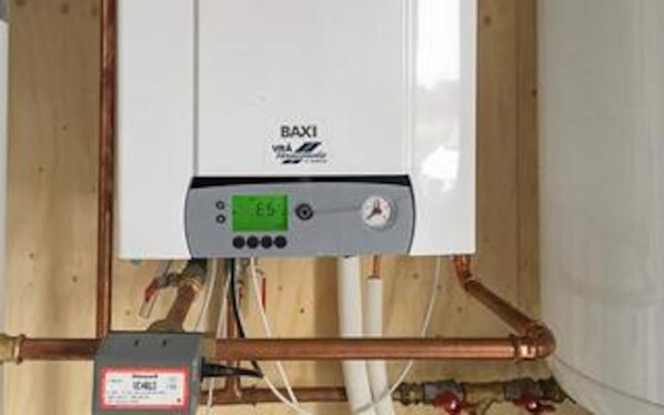 Ein Baxi-Warmwasserbereiter mit digitaler Anzeige, verbunden mit Kupferrohren.