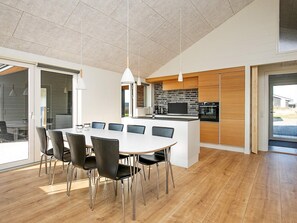 Une cuisine moderne dotée d’un îlot central, de meubles en bois et d’un coin repas avec une table et des chaises blanches.