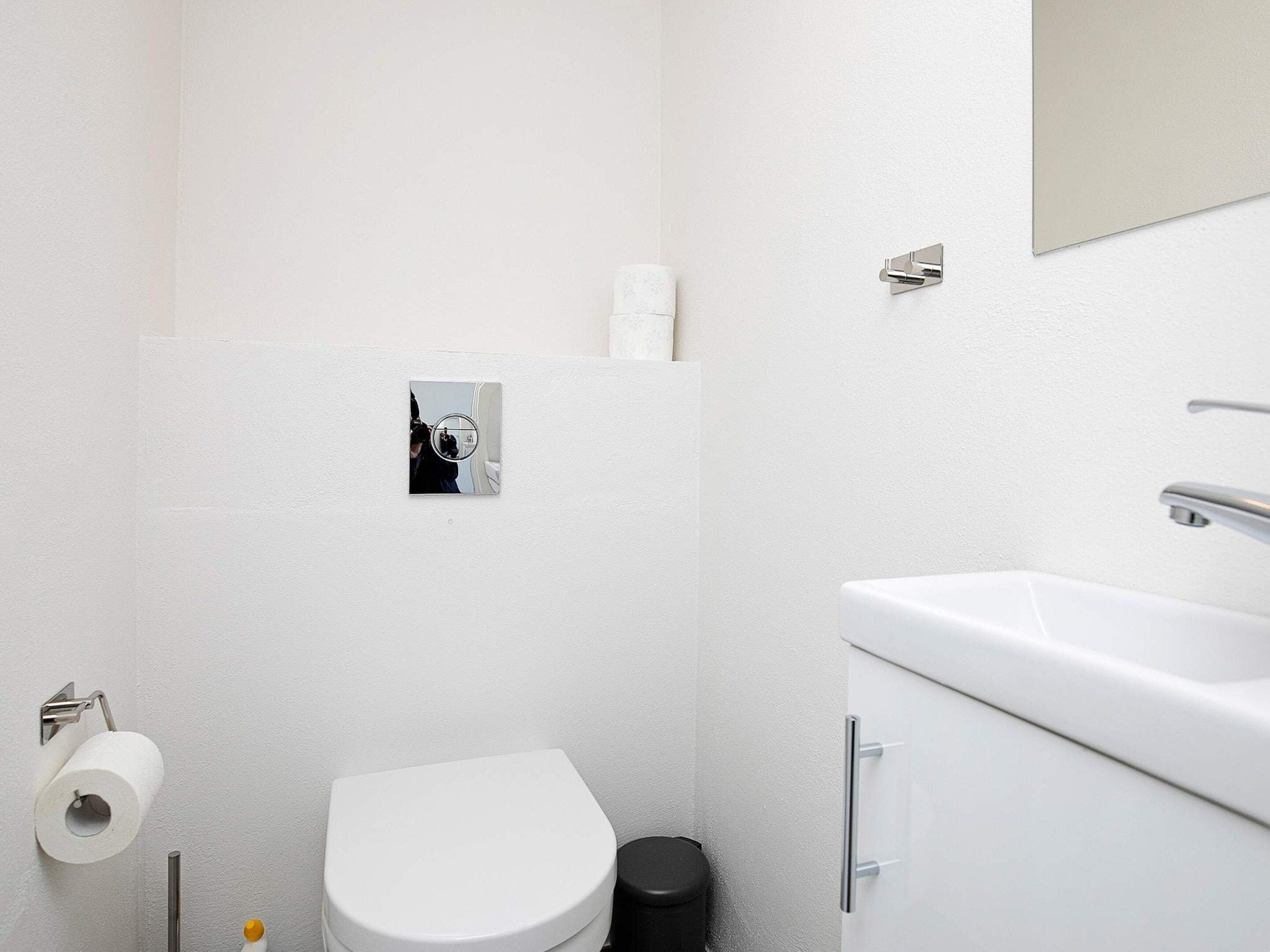 A small, white bathroom with a toilet, a sink, and a mirror.