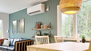 A cozy living room with a wooden table, chairs, a sofa, and a large window with a view of trees. - 6 Person Holiday Home in Albaek-by Traum (Aalbaek)
