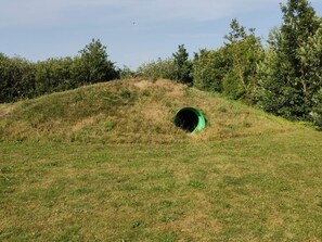 A grassy hill with a green tunnel entrance.