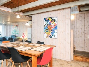 A modern interior with a wooden table, chairs, and a colorful abstract painting on the wall.
