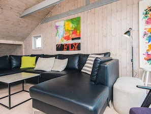 A modern living room with a sectional sofa, a small table, and a painting on the wall.