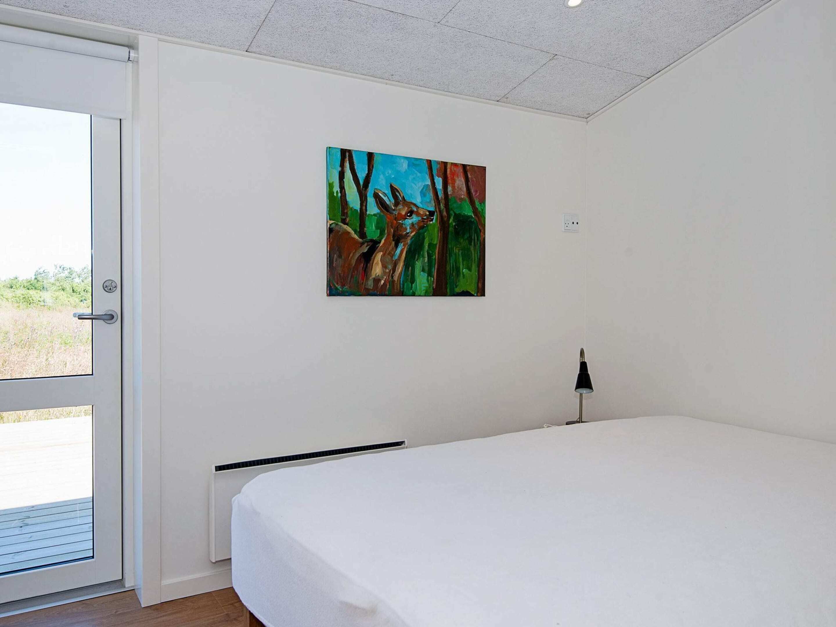 Quarto com cama, porta, quadro e abajur.